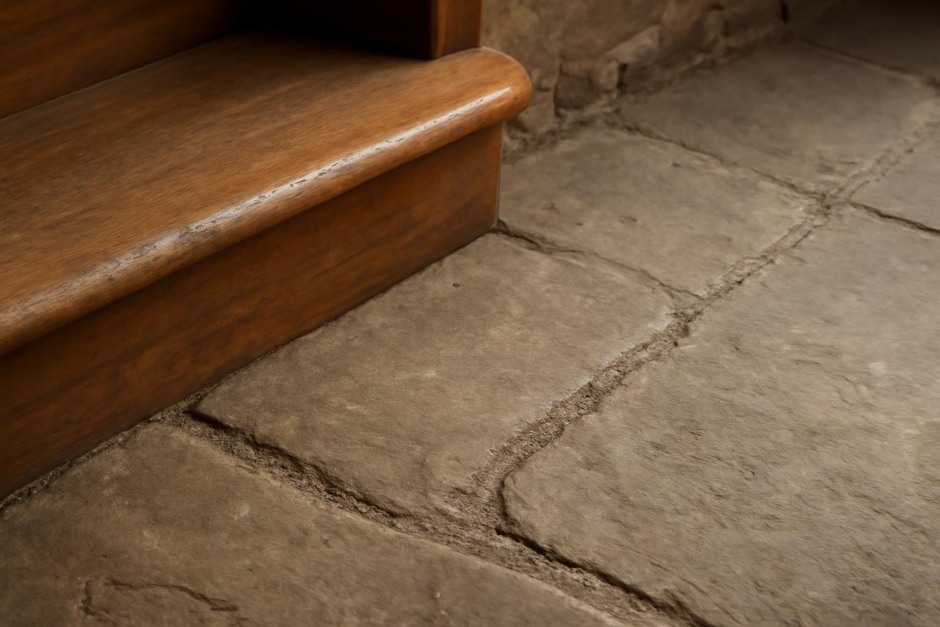 Close-up of a polished wooden stair nose and a worn path in flagstone